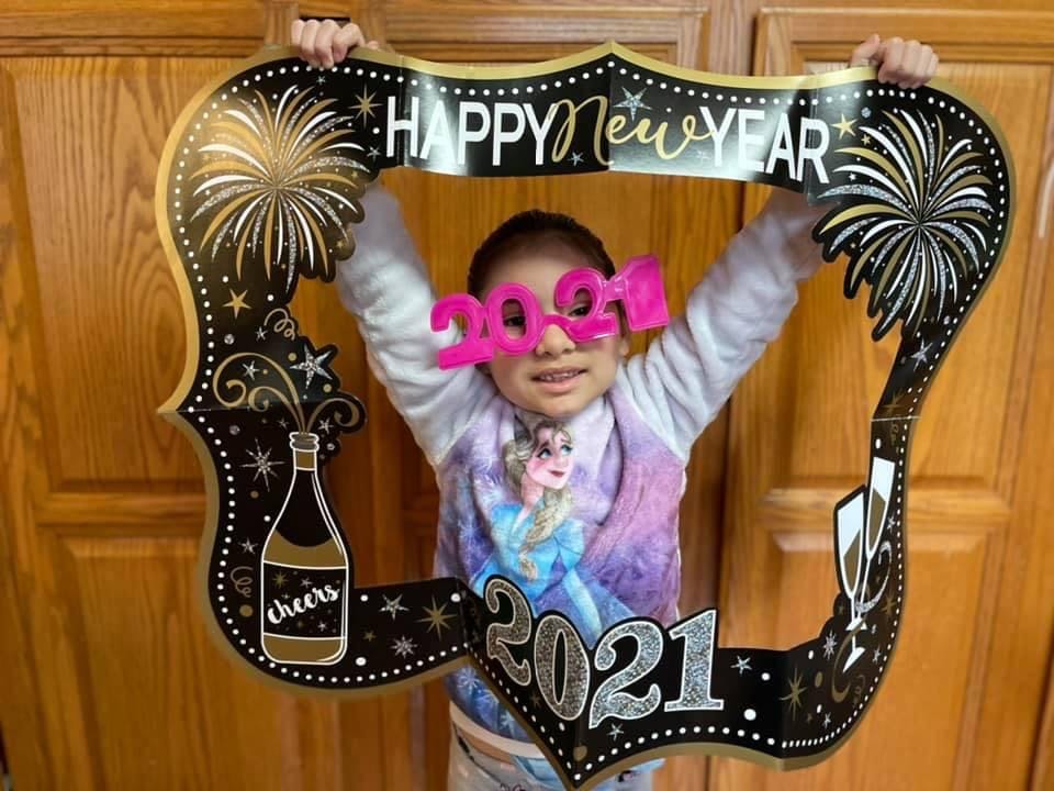 Child wearing 2021 glasses holding a Happy New Year photo frame