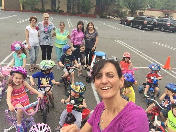 Adults and children on bikes and tricycles in a parking lot