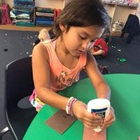 Child gluing paper at a table