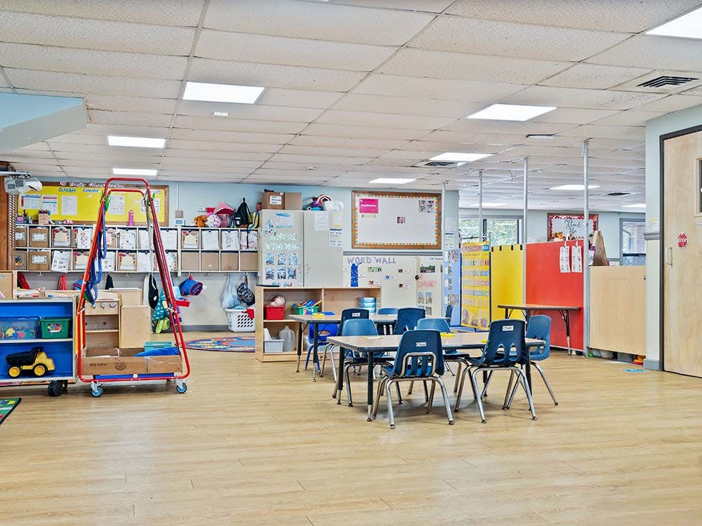 Empty classroom with small blue tables and chairs
