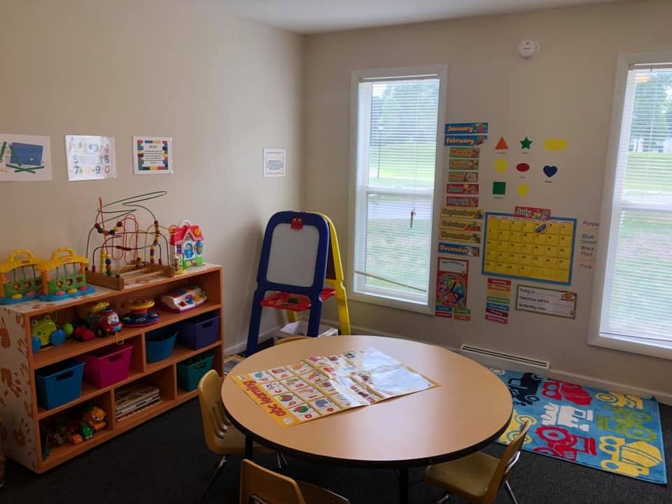 Classroom with a round table, chairs, and shelves with toys