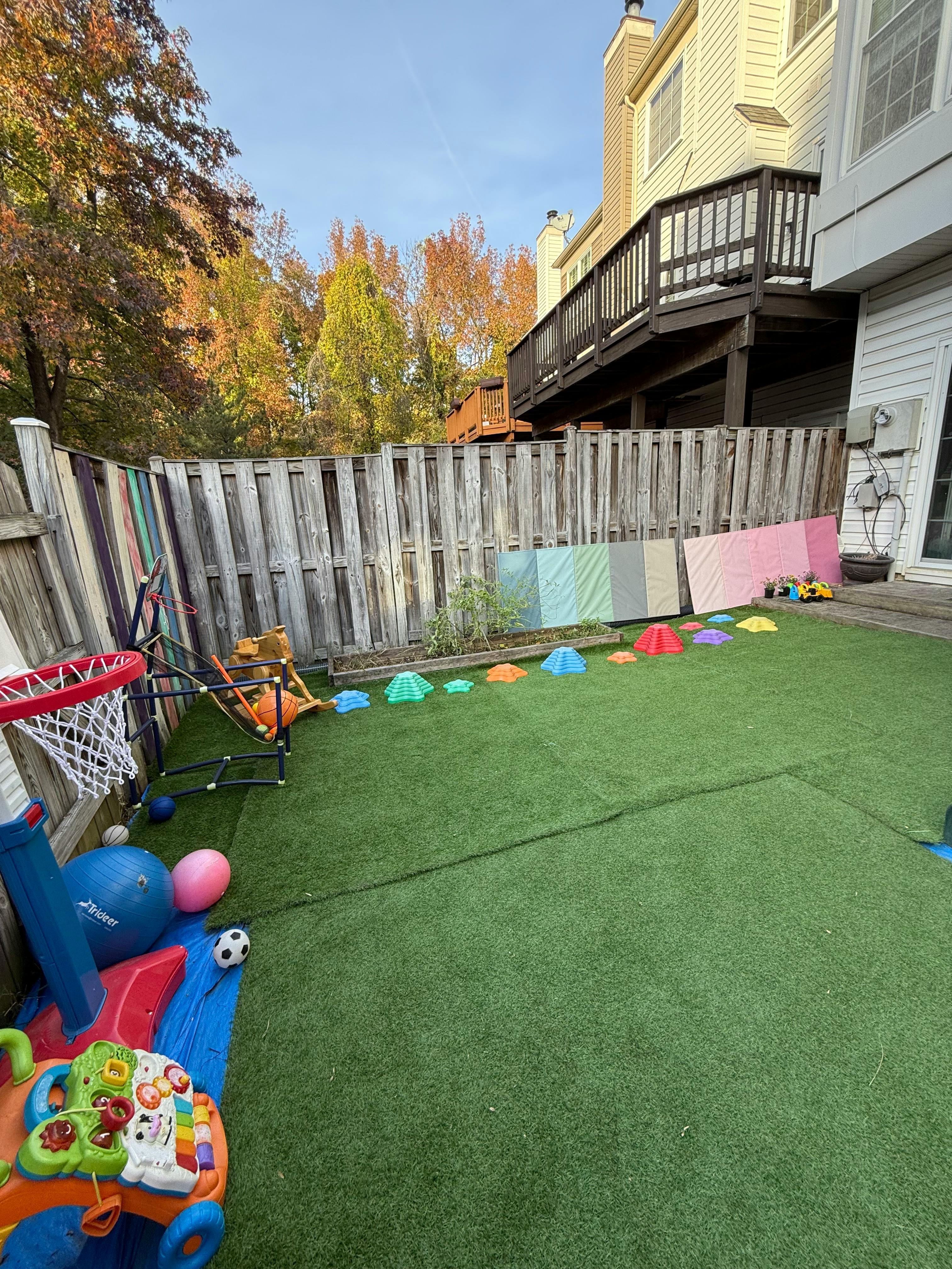 Backyard with artificial turf, basketball hoop, and colorful play equipment