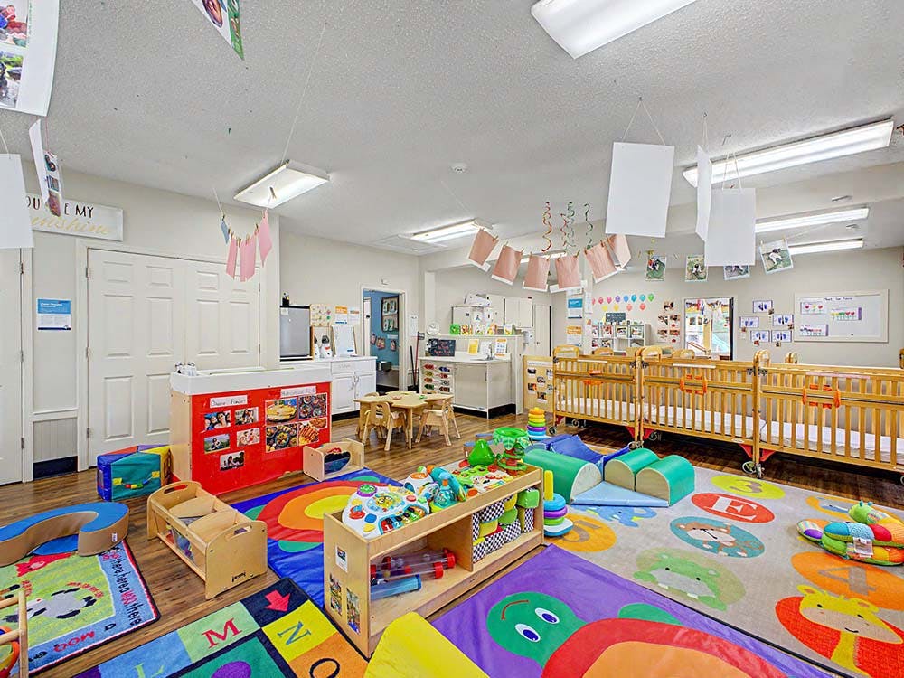 Baby nursery room in a daycare with several cribs and colorful playmats