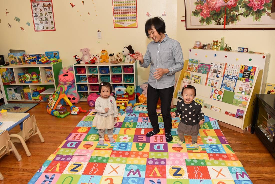 Adult and two children standing on an alphabet playmat in a playroom