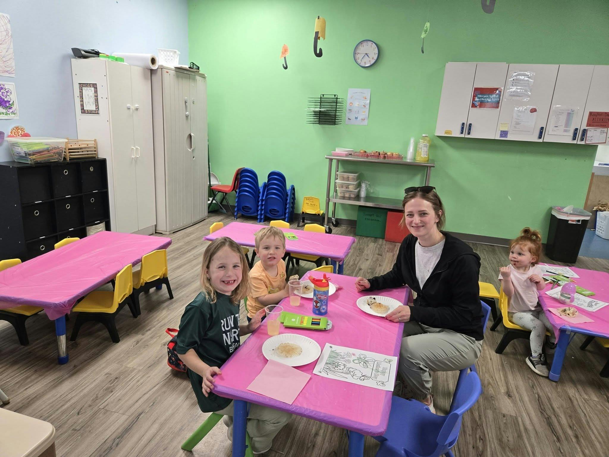People sitting at a table with plates and coloring pages in a classroom