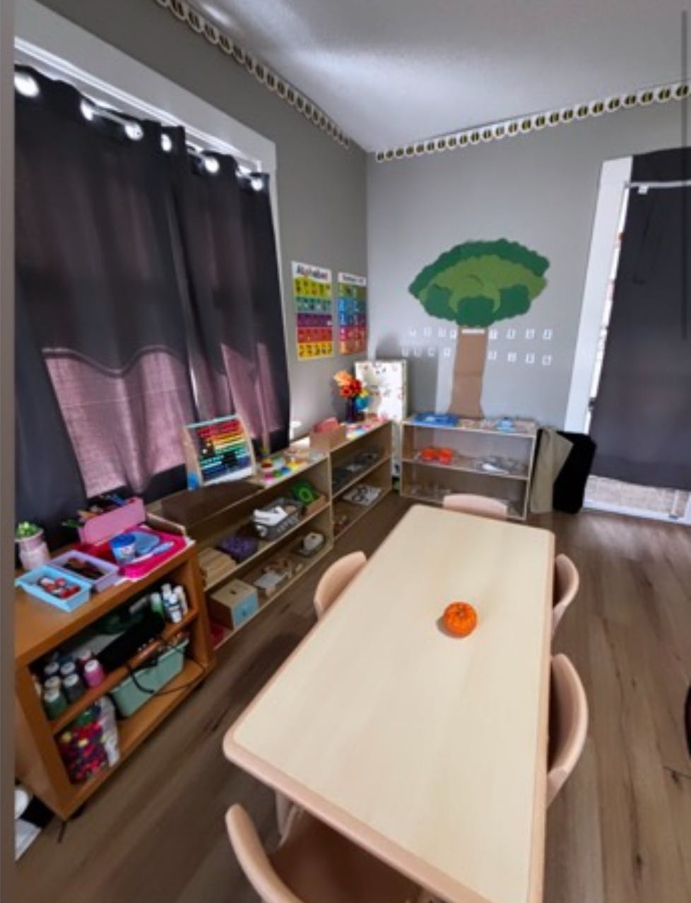 Classroom with a table, chairs, shelves with learning materials, and wall decorations