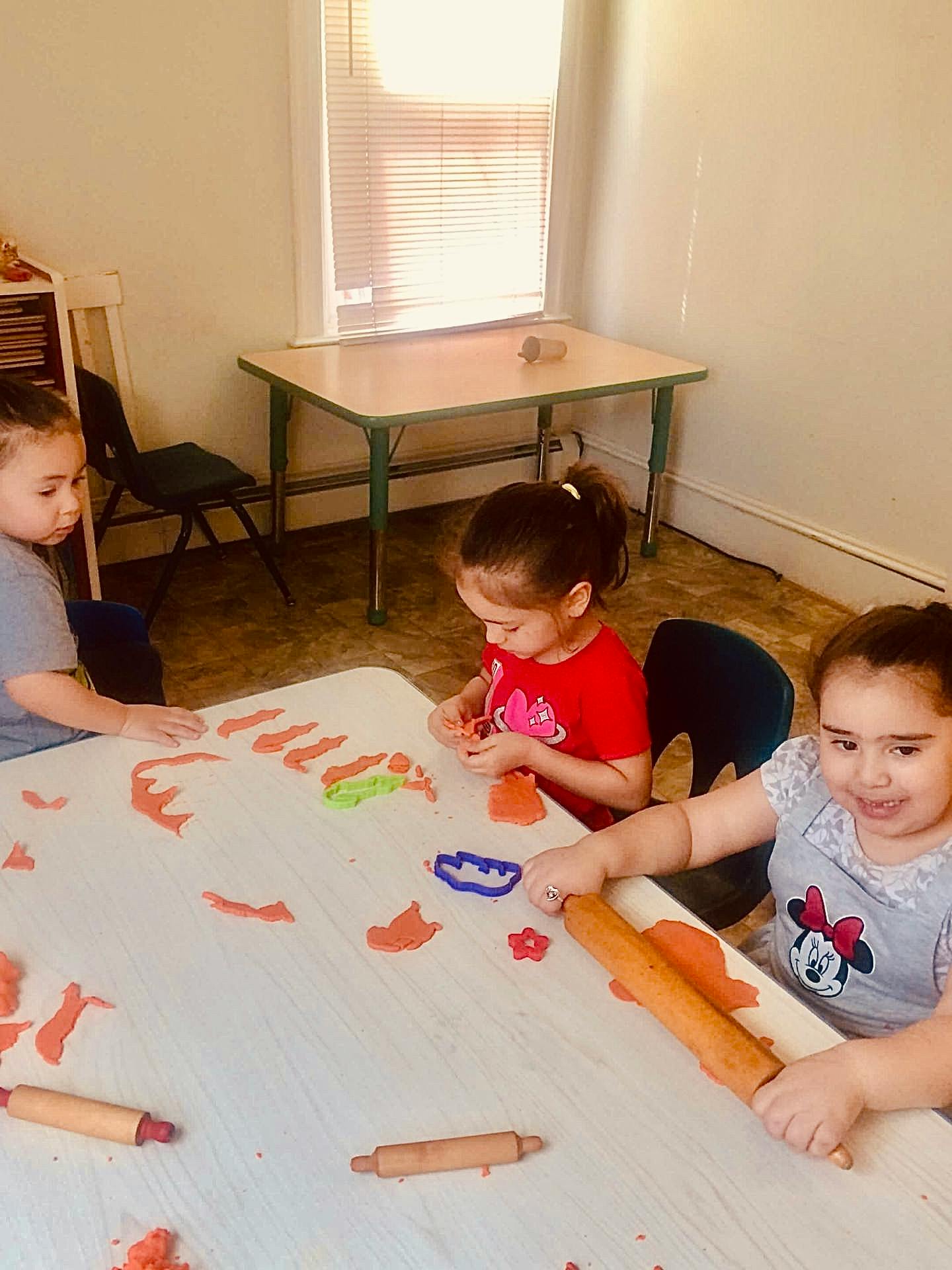 Three children playing with modeling clay at a table