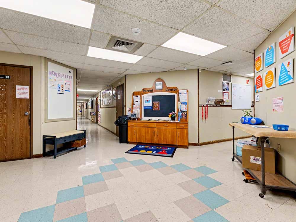 Hallway with a bulletin board and a welcome mat leading to a parent center