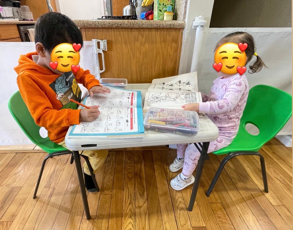 Two children sitting at a table with coloring books