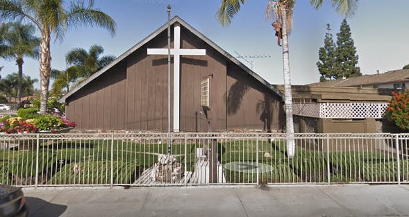 Brown church building with a white cross on the front