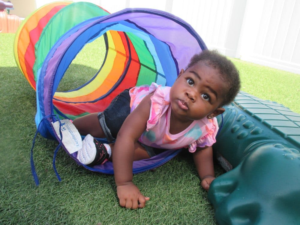 Child crawling out of a colorful play tunnel