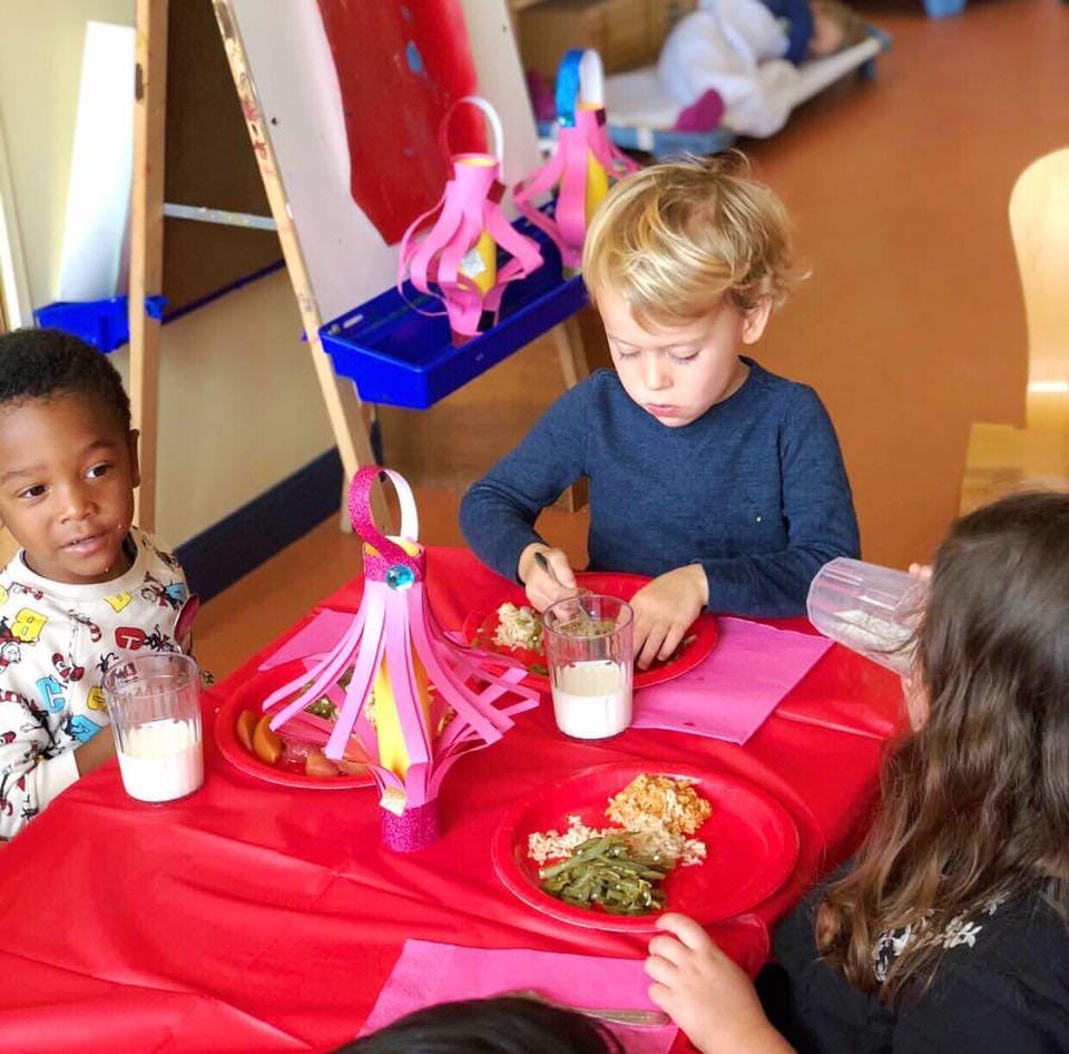 Children eating at a table in a classroom