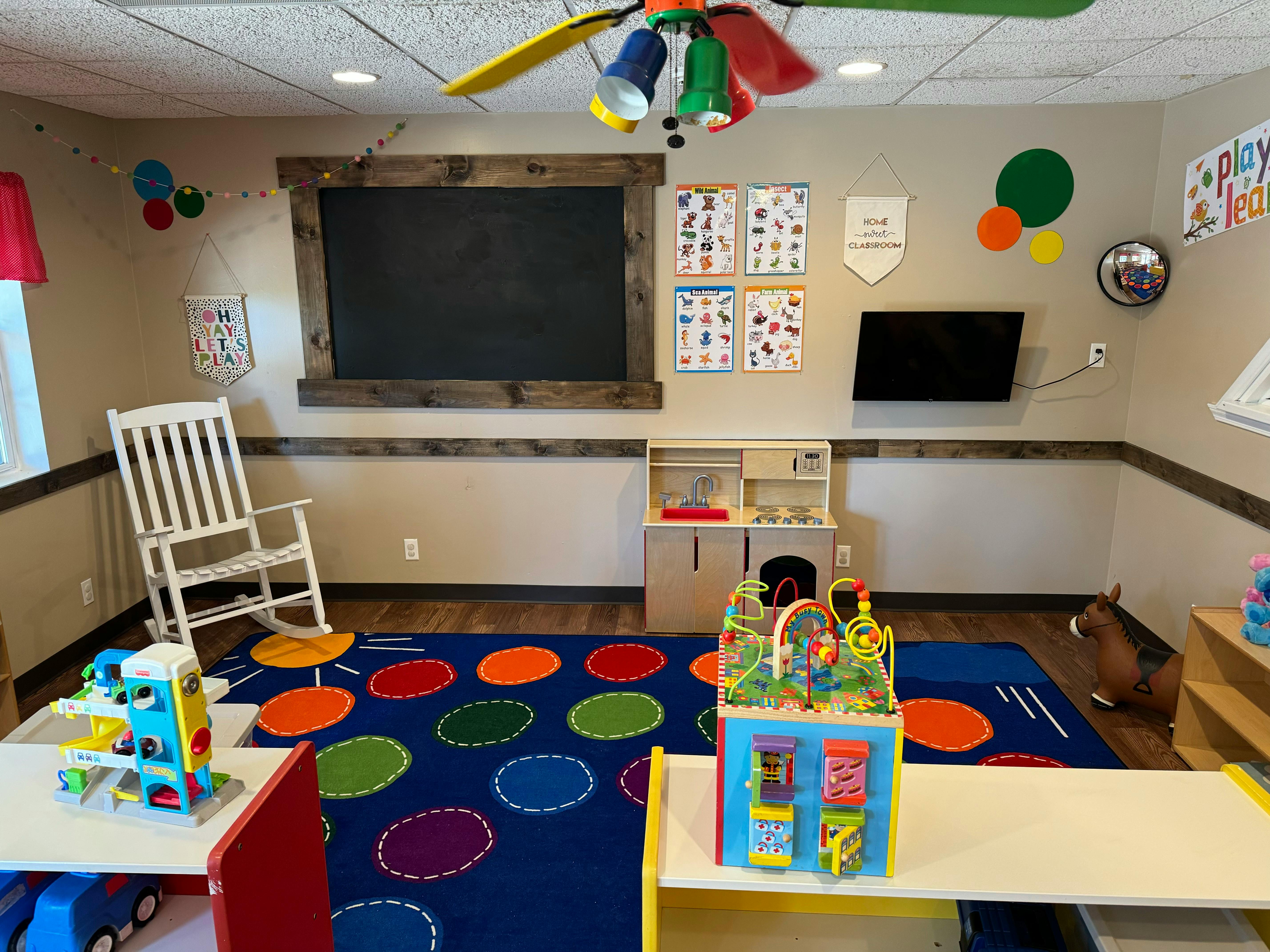 Classroom with a chalkboard, colorful rug, and toys