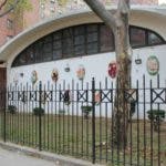 Building with arched windows and colorful decorations behind a black fence