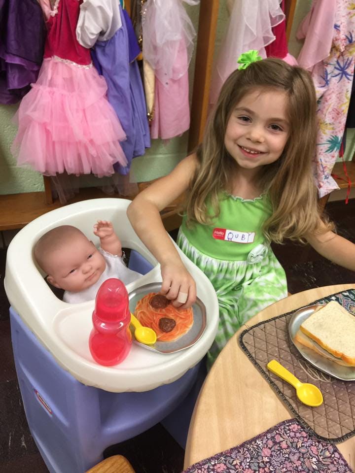 Child feeding a baby doll in a high chair