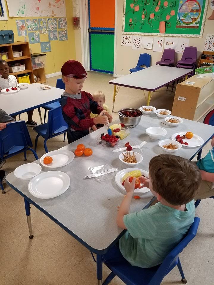 Children preparing fruit at a table