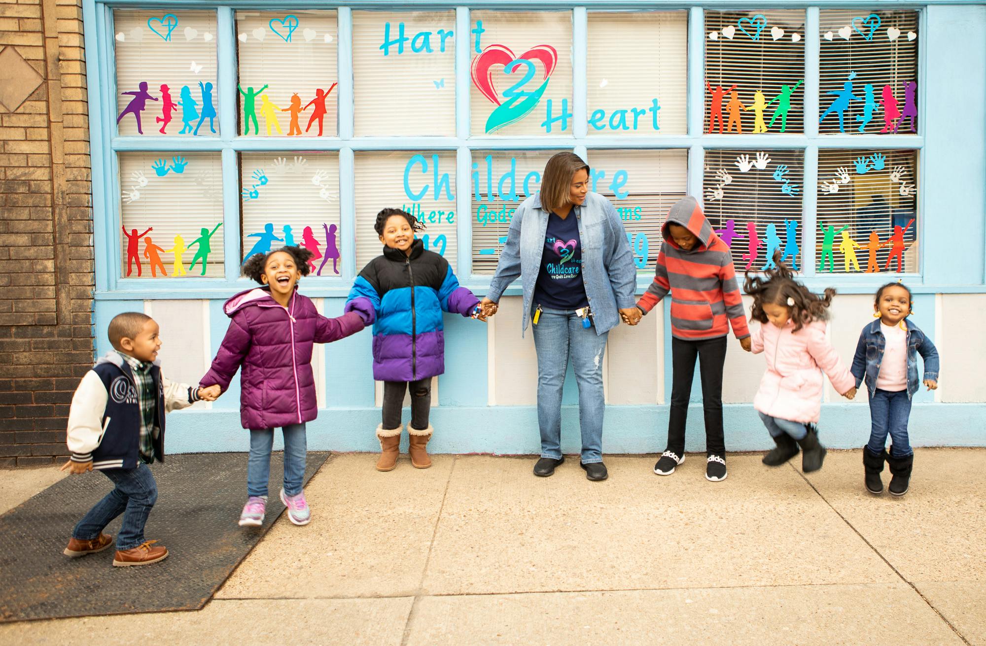 Adult and children holding hands in front of a building
