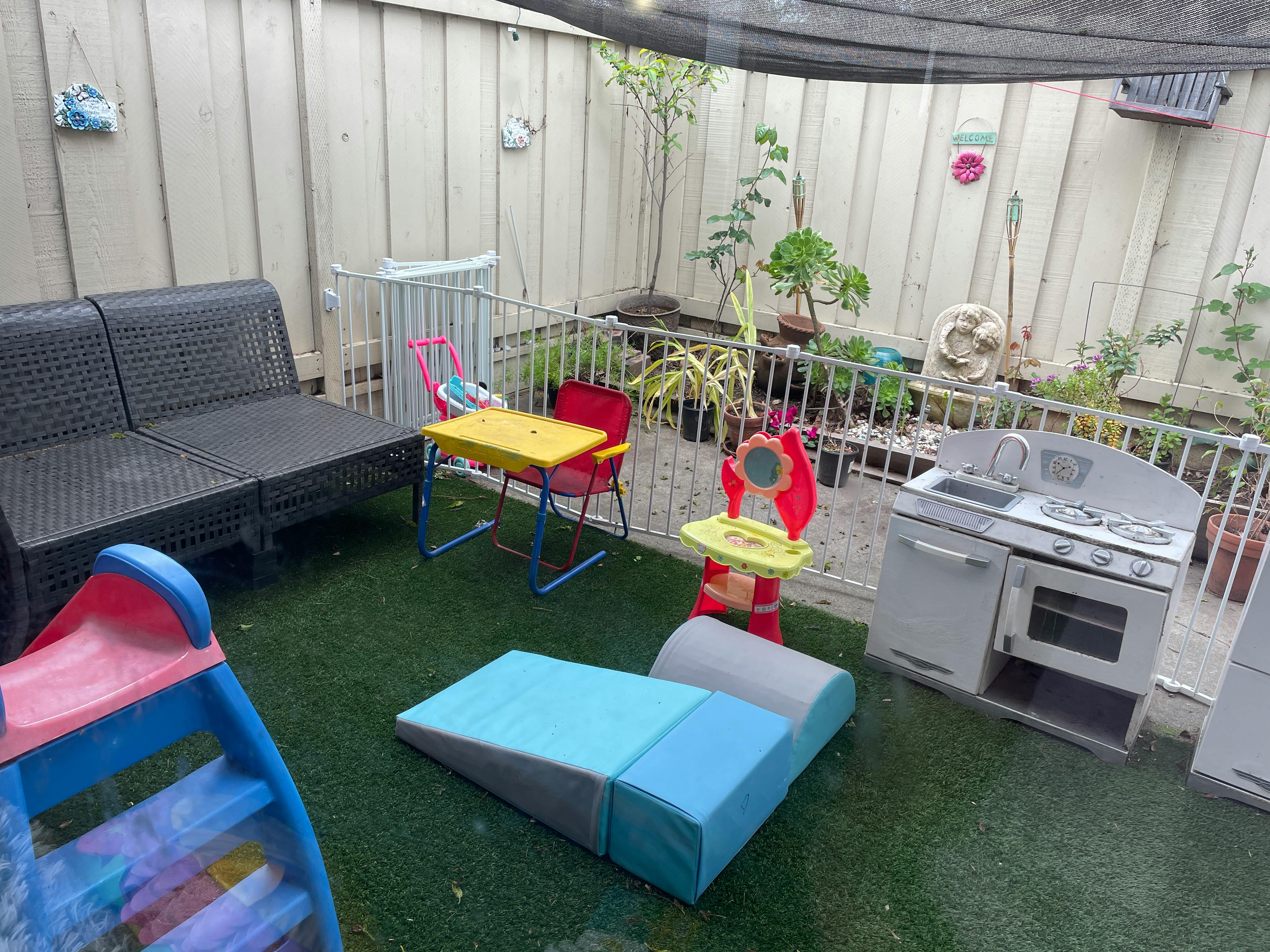 Outdoor play area with a small slide, soft play blocks, and toy kitchen