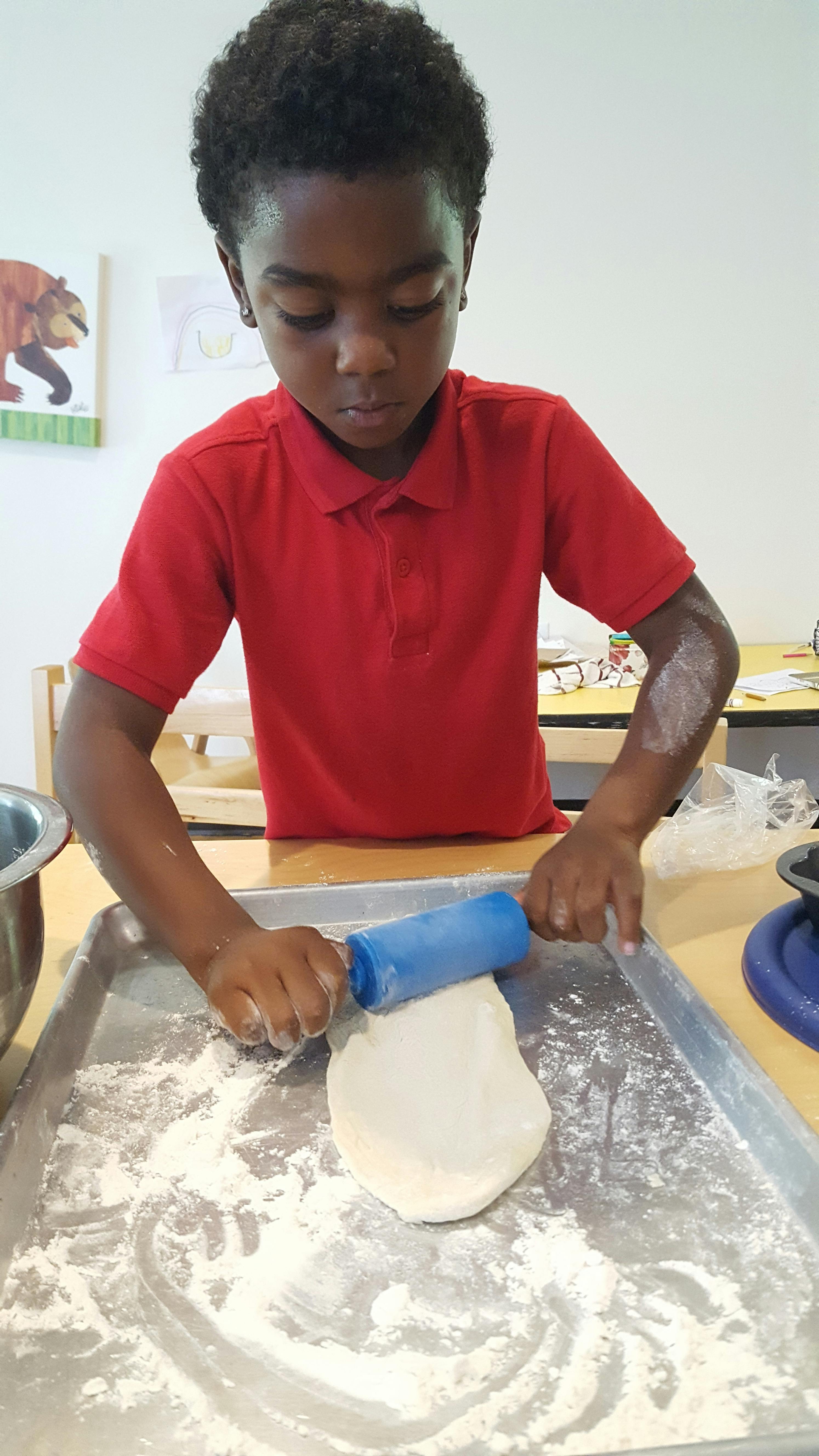 Child rolling dough on a baking sheet