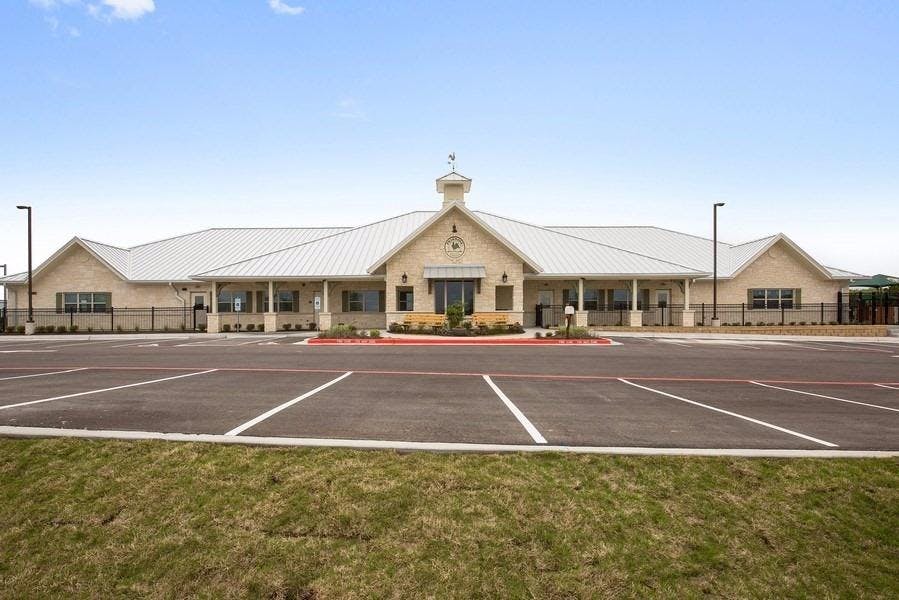 Large building with a cupola and a parking lot in front