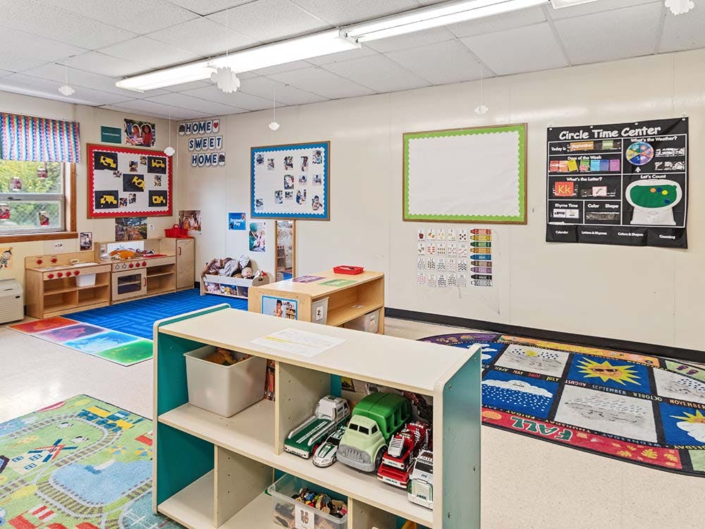 A classroom with activity rugs, play kitchens, and learning charts on the walls