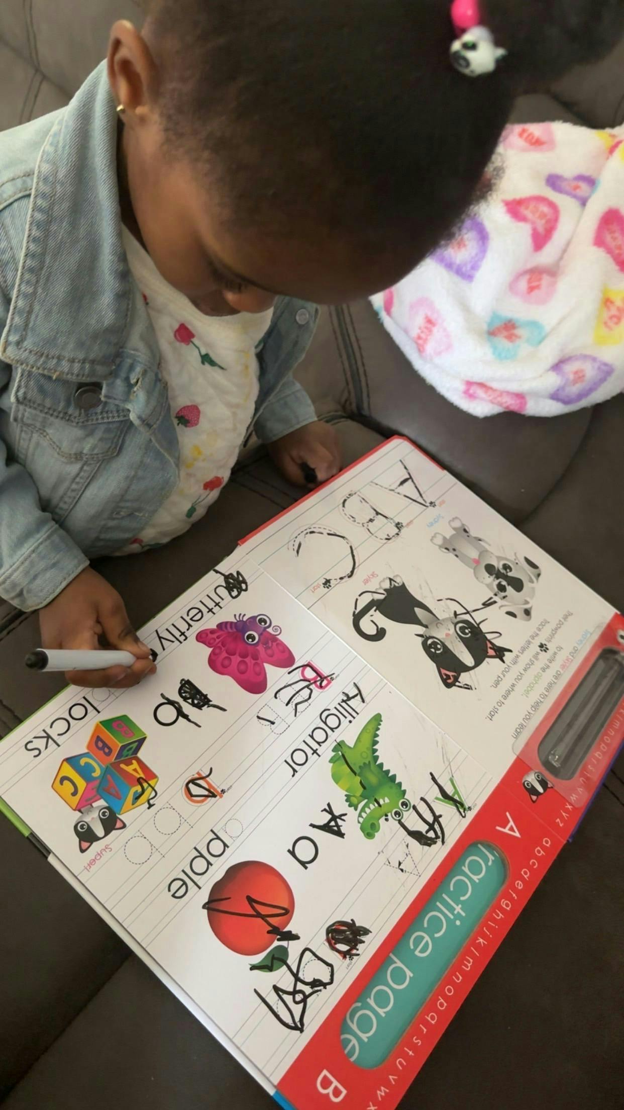 Child writing on an alphabet practice page