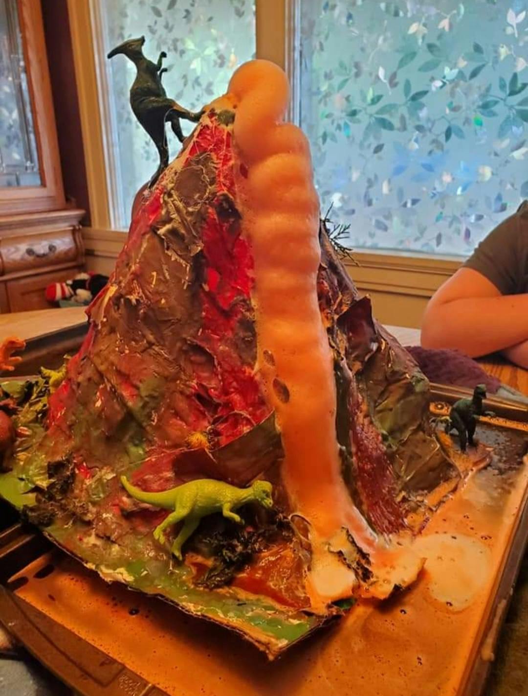 Volcano science project with toy dinosaurs and orange foam eruption