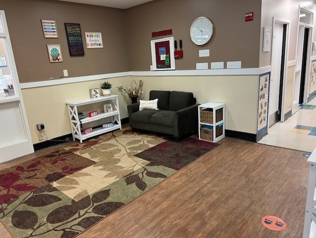 Lobby area with a small couch, a rug with leaf patterns, and wall decorations