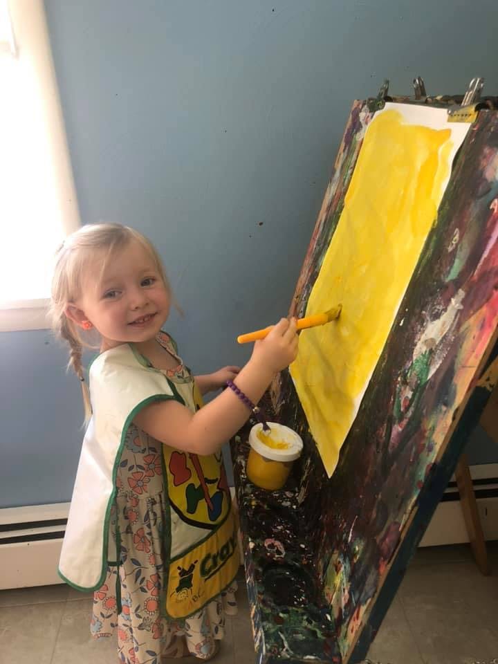 Child painting on an easel with yellow paint