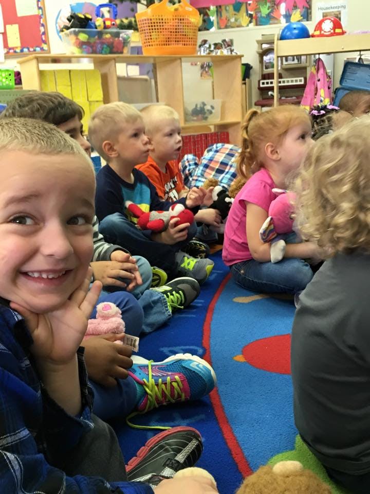 Child smiling at camera while sitting with other children