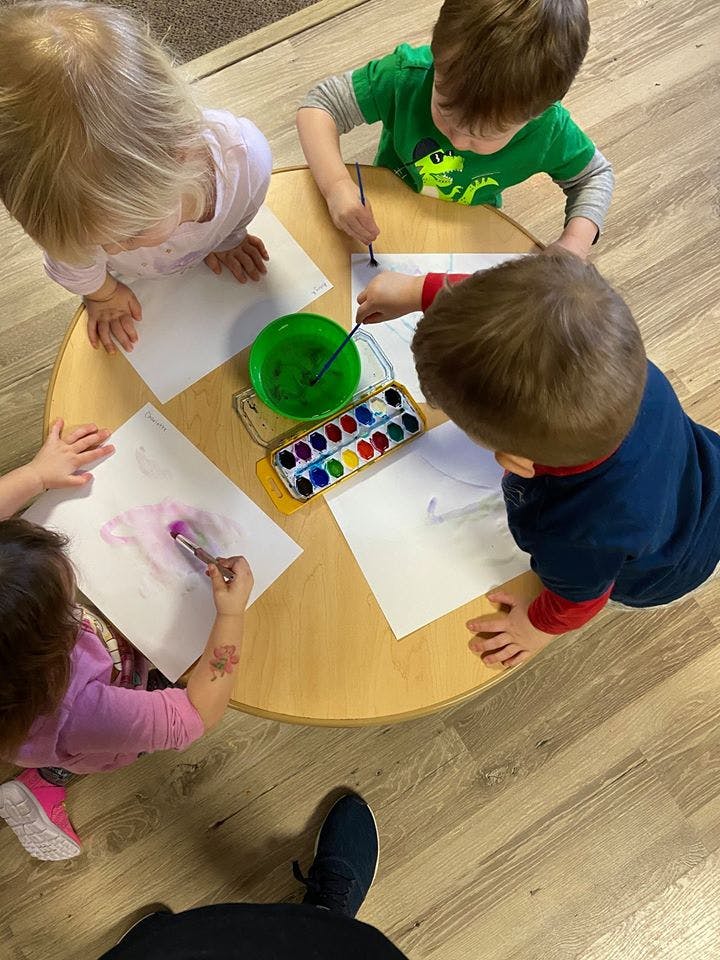 Children painting at a small round table