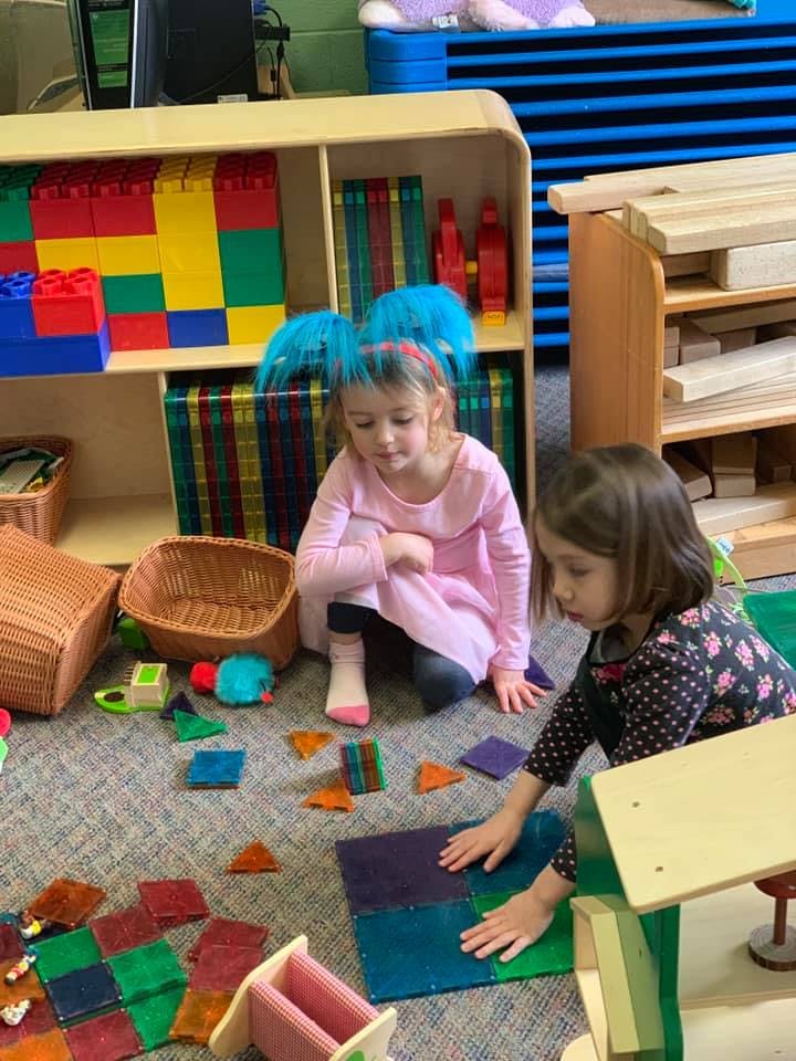 Two children playing with colorful magnetic tiles on the floor