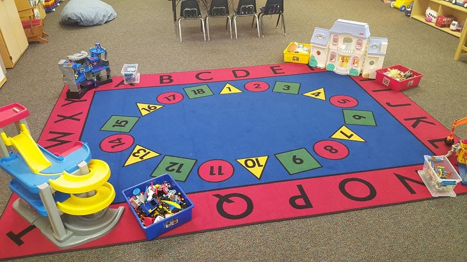 Playroom with a colorful rug featuring letters and numbers, toys scattered around