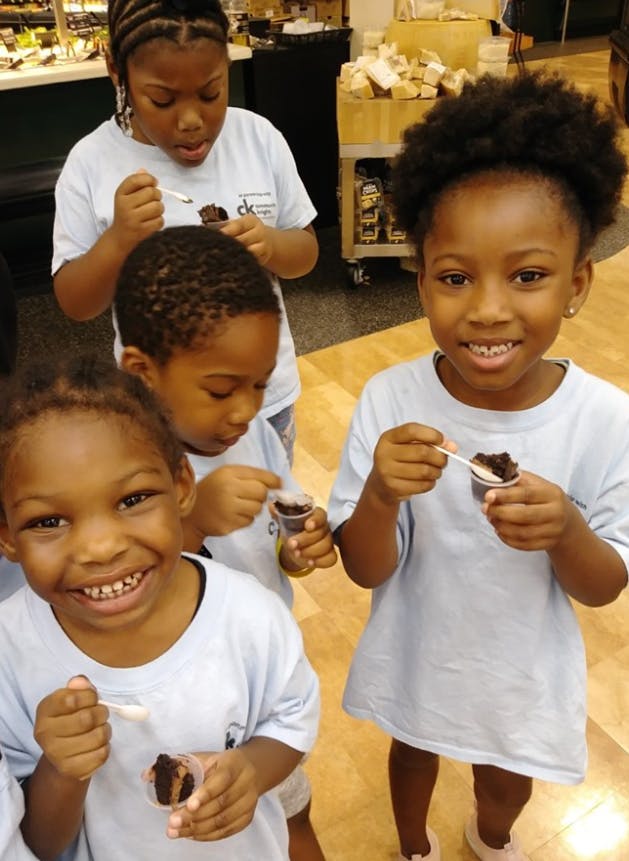 Four children eating from small cups with spoons