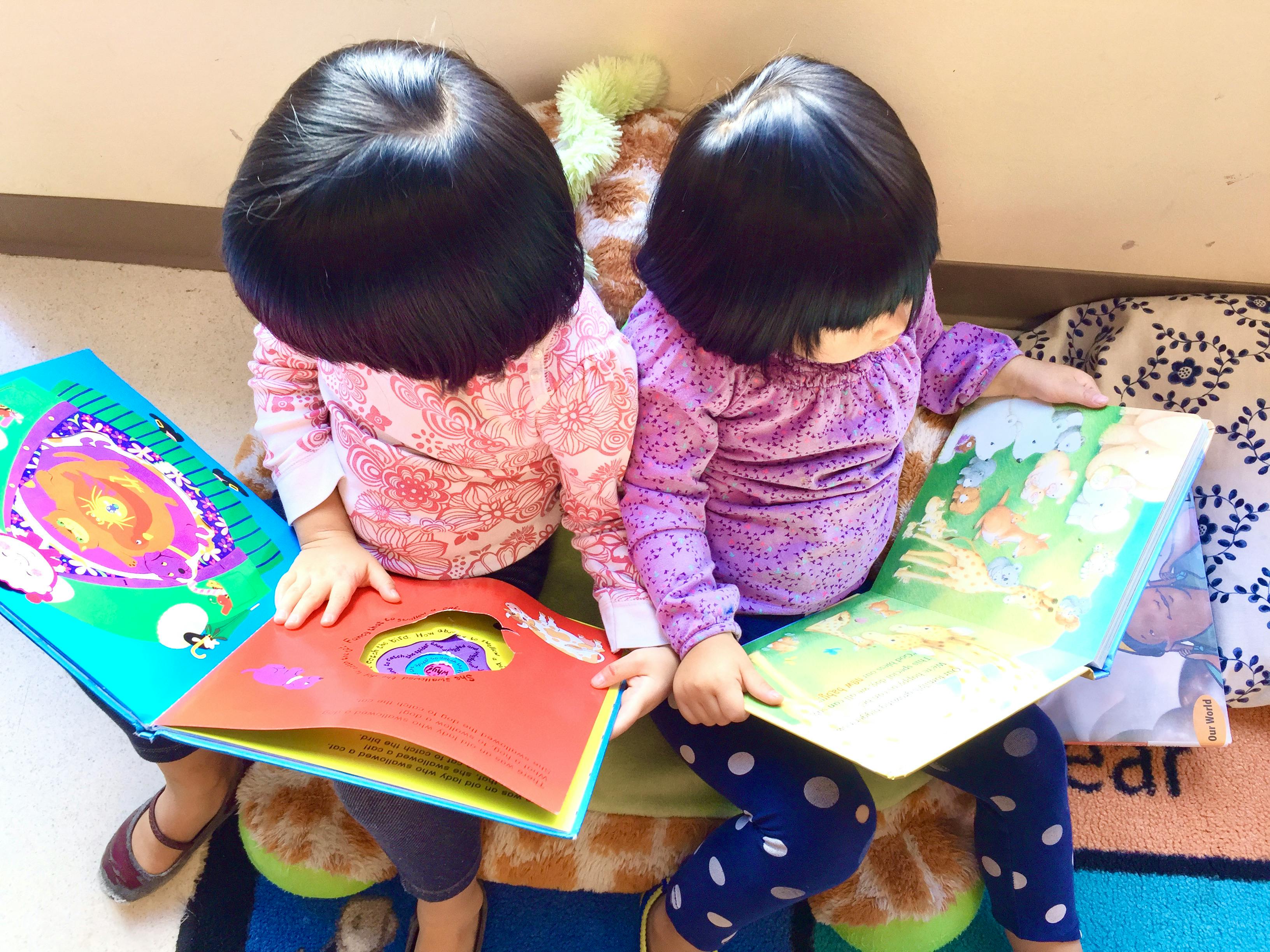 Two children sitting on the floor reading picture books