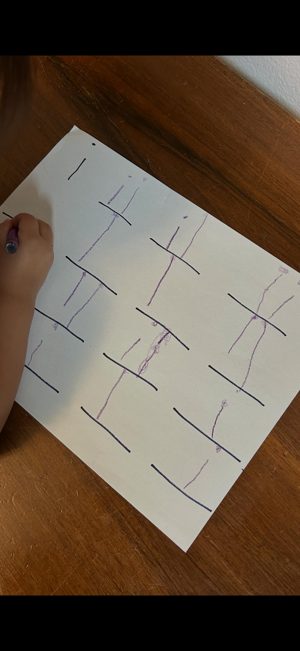 Child writing lines and vertical marks on paper