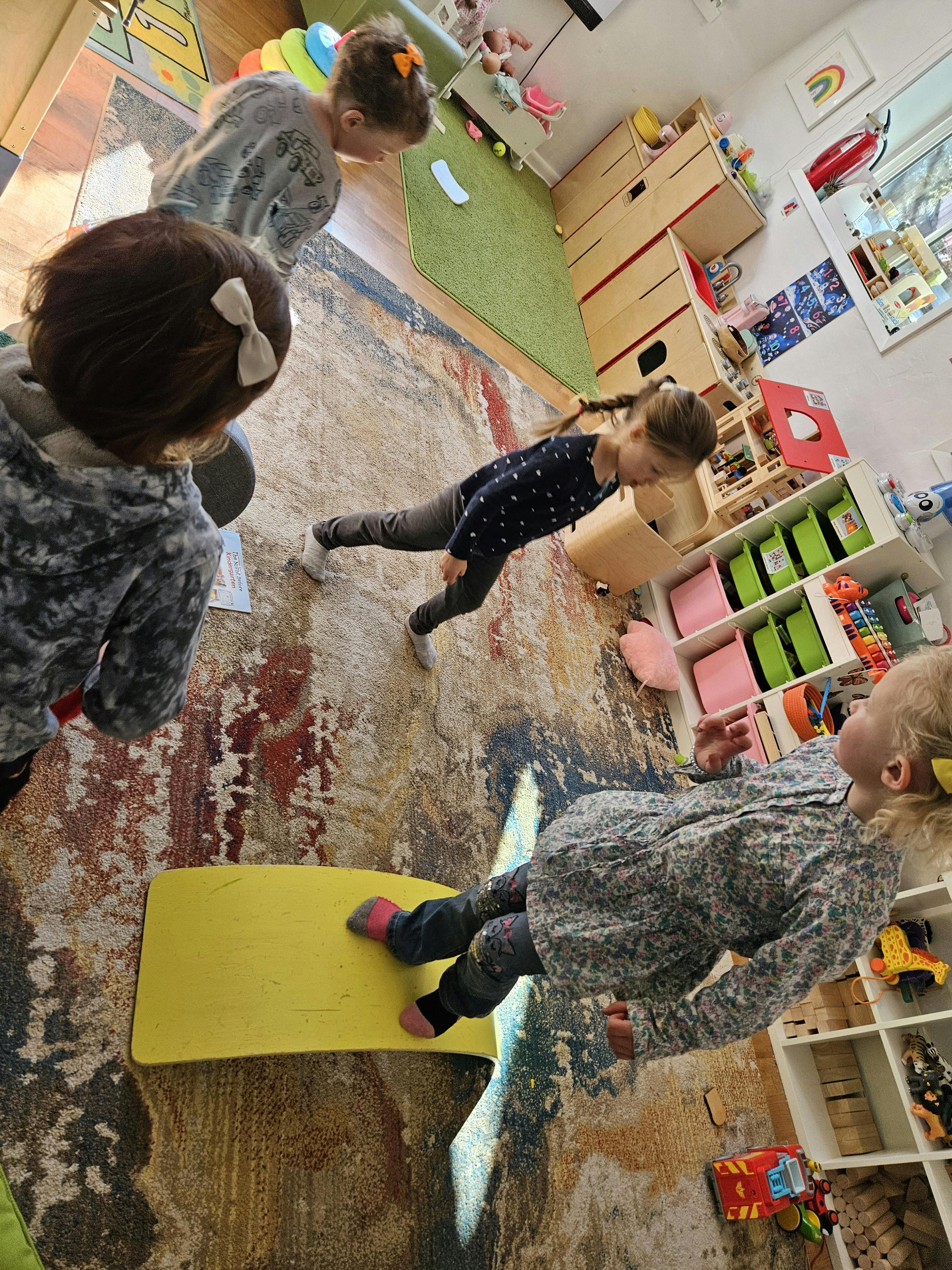 Children playing on a rug in a room with shelves