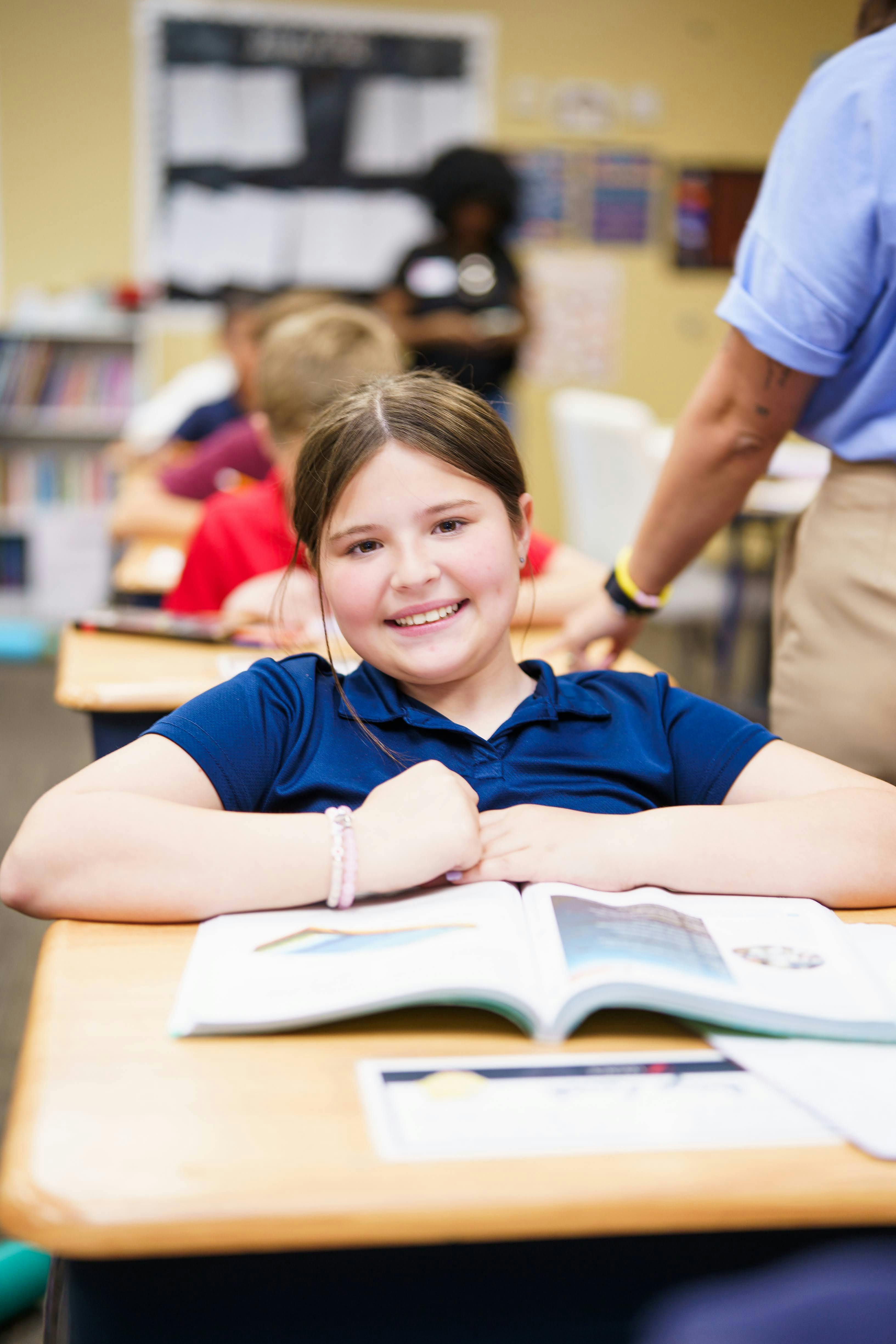 Child sitting at a desk with an open book in a classroom