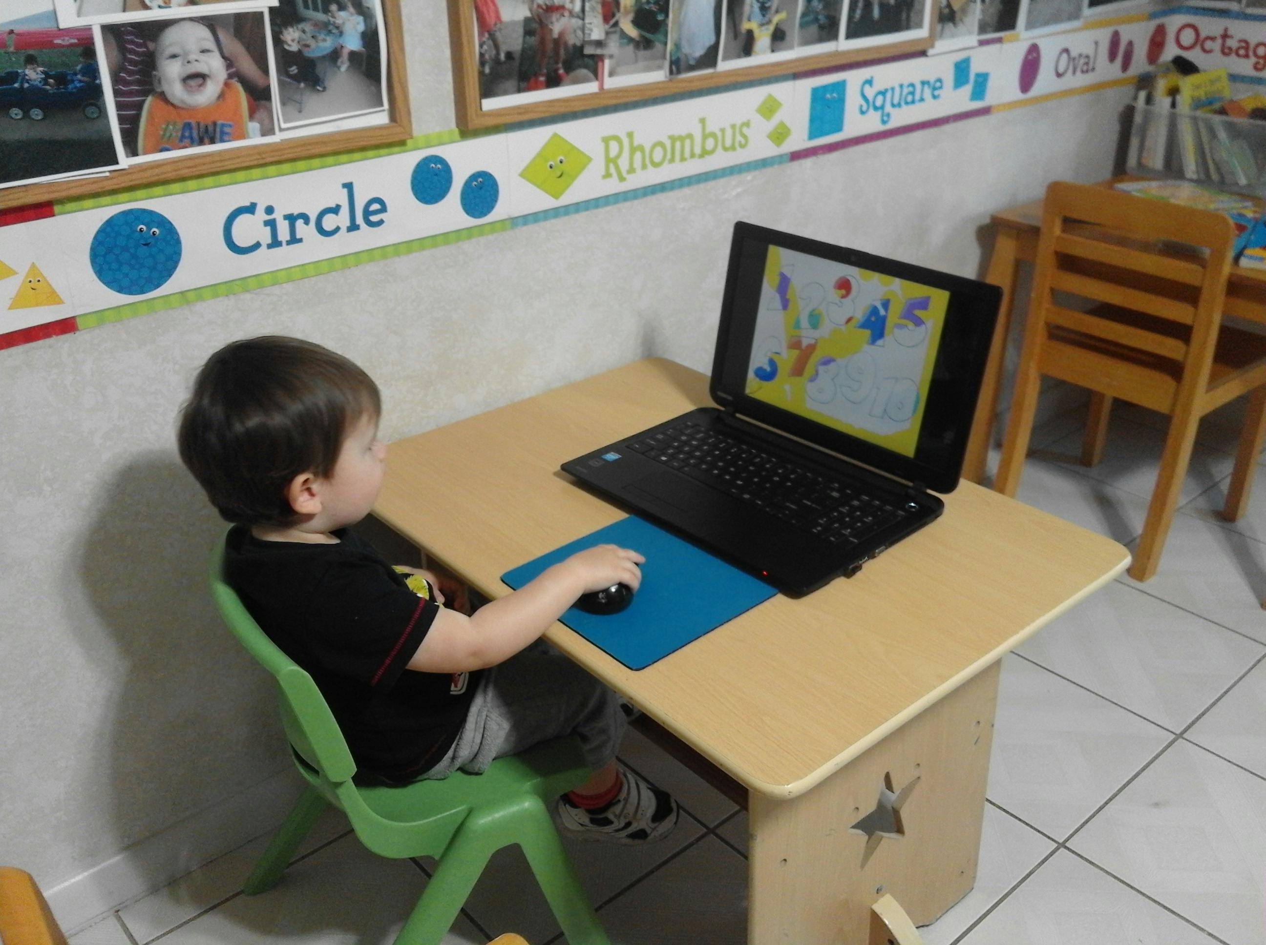 Child sitting at a desk using a laptop with a mouse