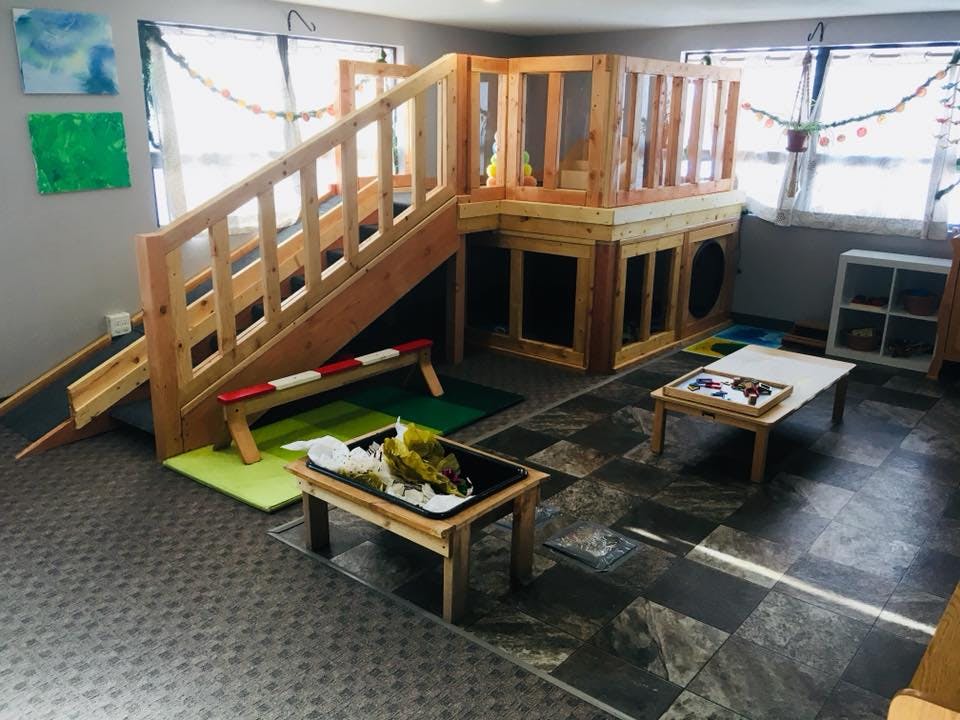 Indoor play structure with stairs, slide, and activity tables