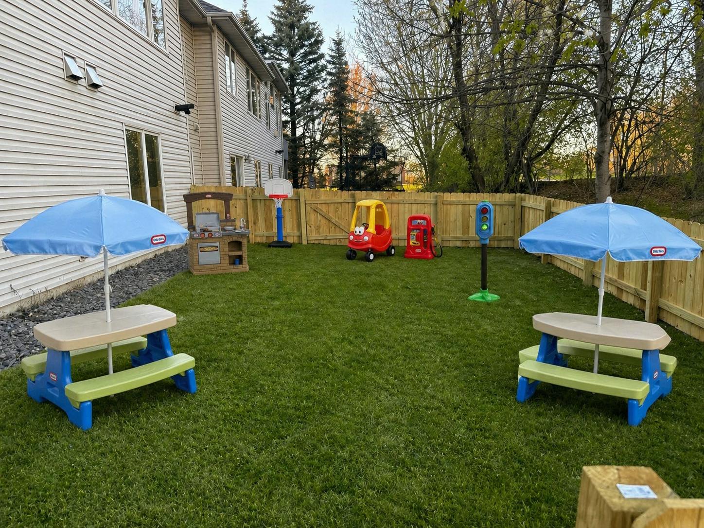 backyard play area with toy picnic tables, basketball hoop, car, gas pump, traffic light