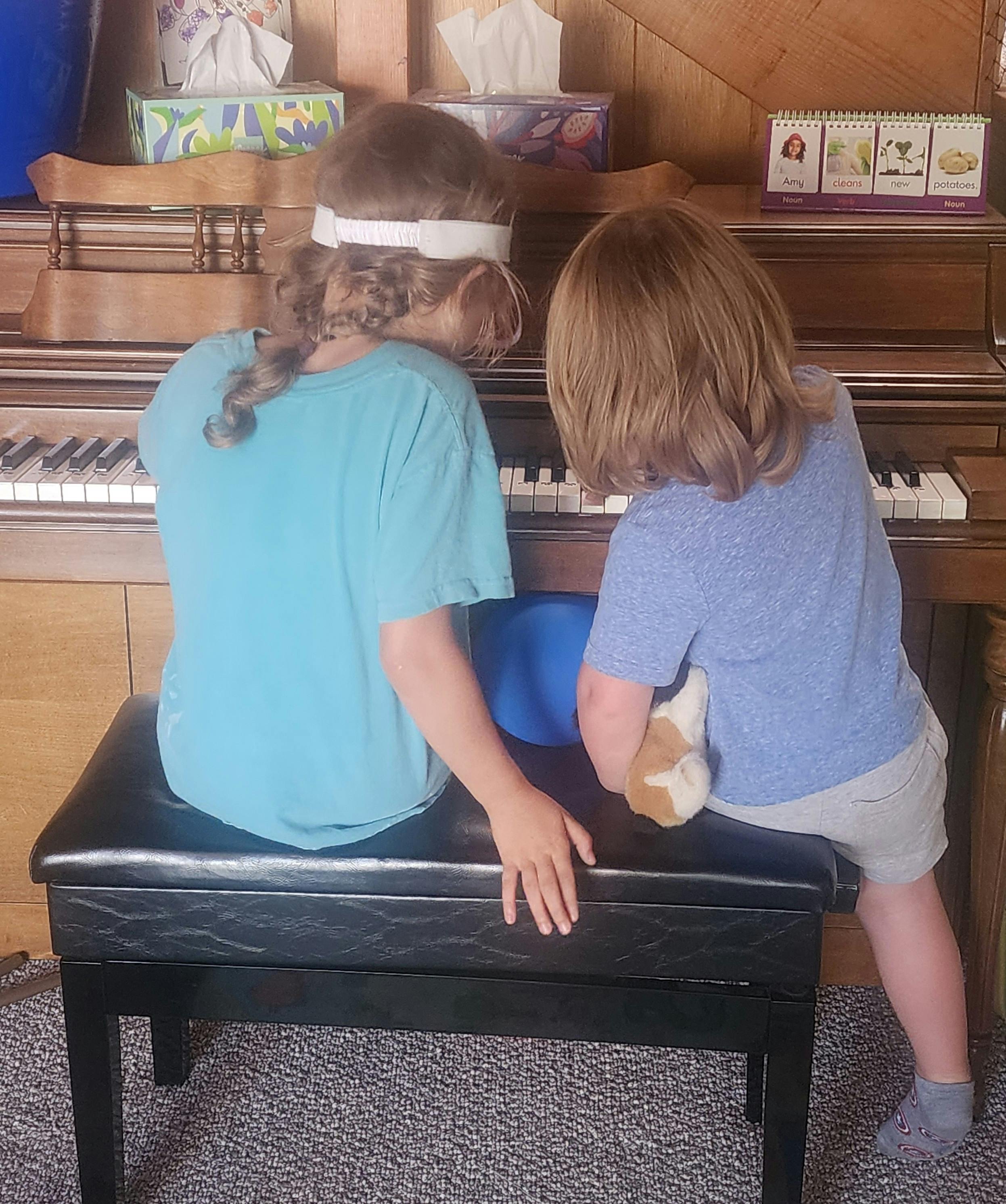 Two children sitting at a piano