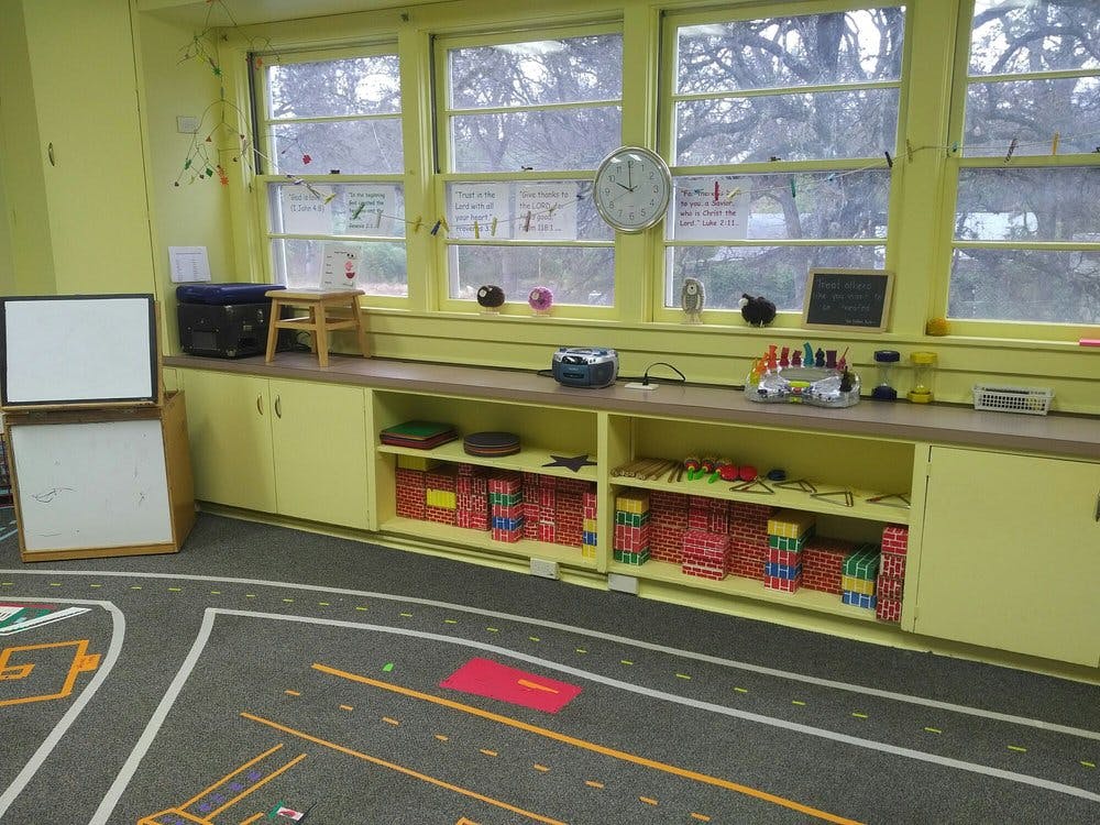 Classroom with windows, shelves of books, and a road map rug