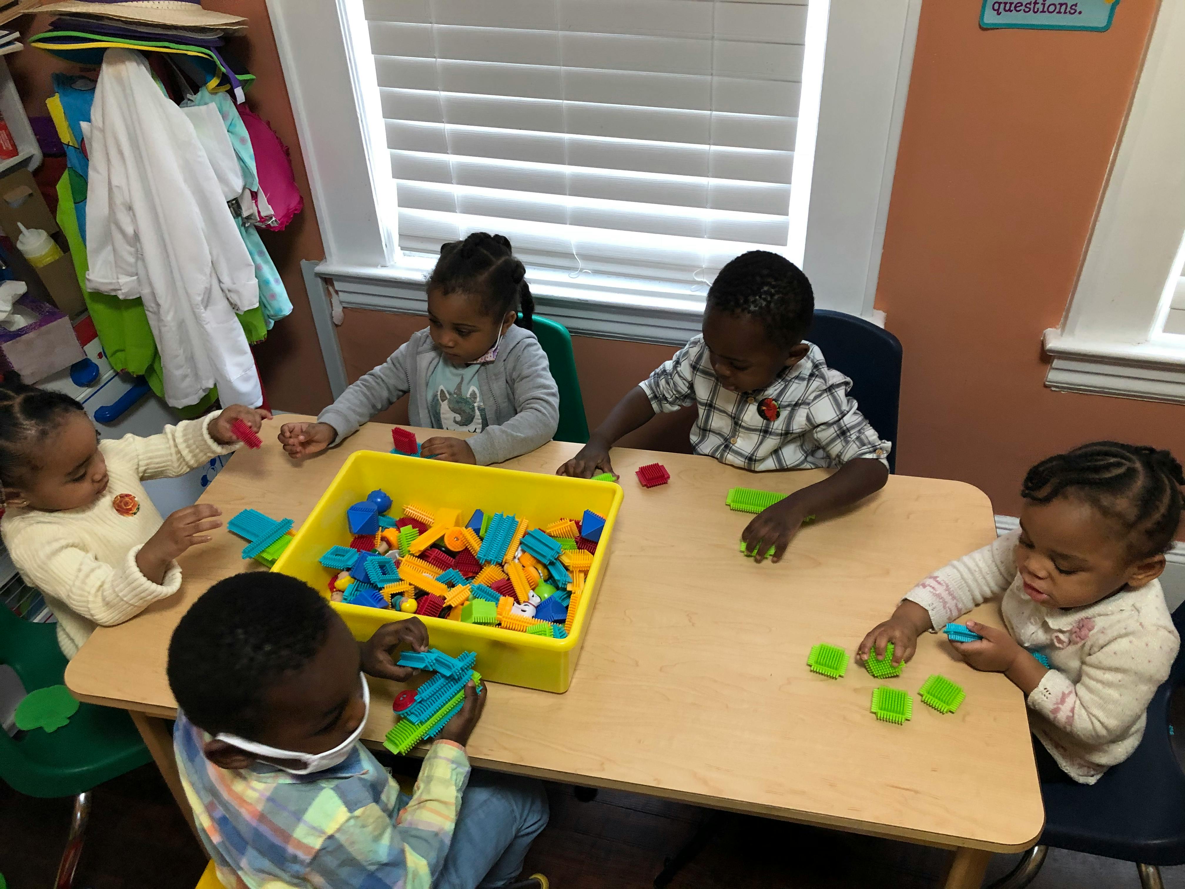 Children playing with colorful blocks at a table in a classroom