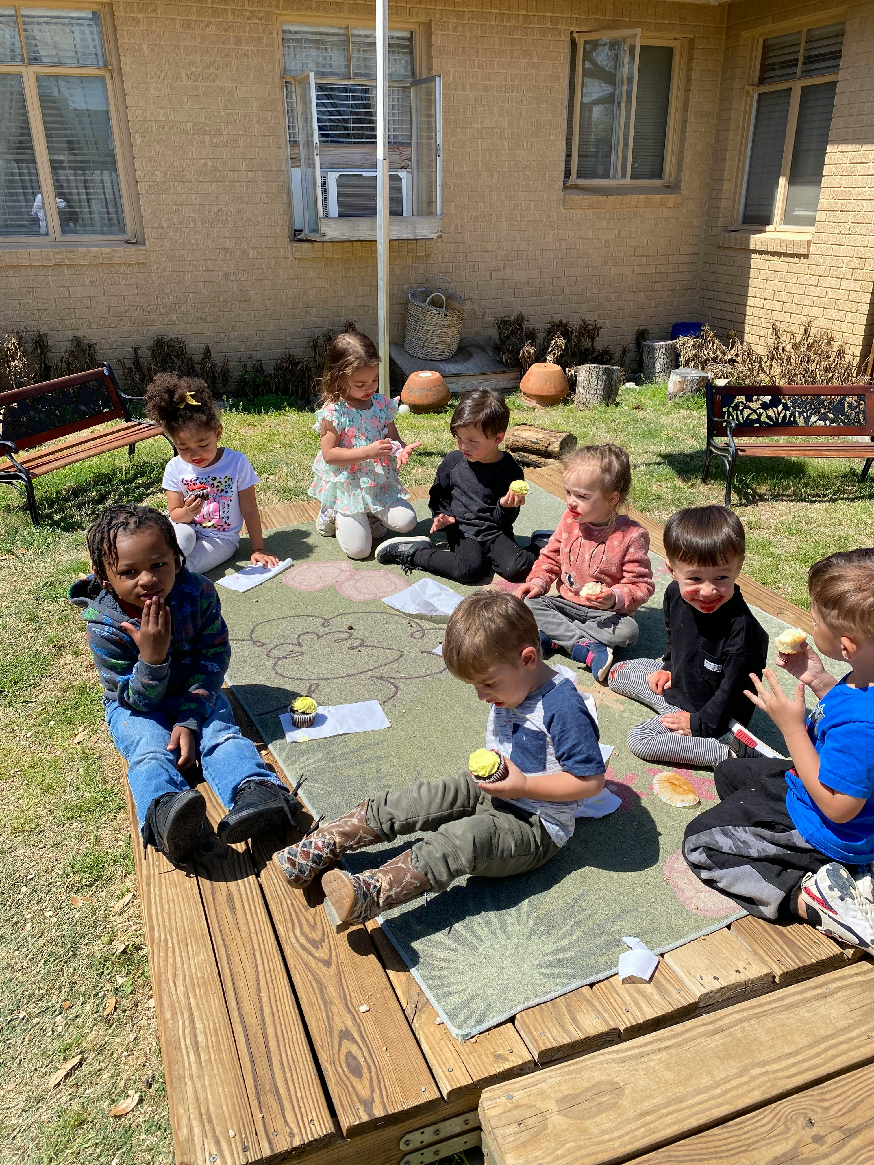 Children sitting on a mat outdoors