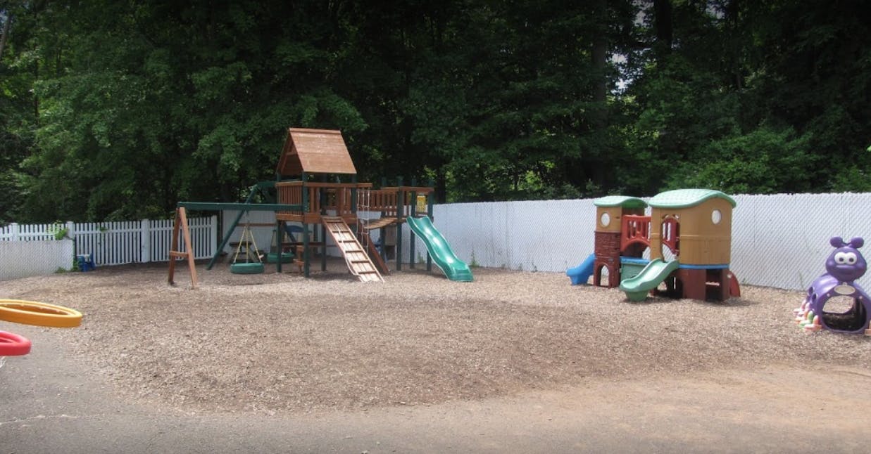 Outdoor playground with wooden playset, slides, and plastic playhouse
