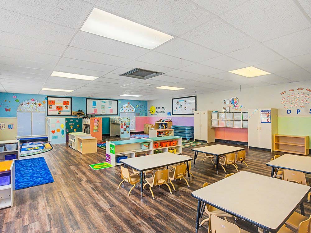 Empty colorful preschool classroom with small tables and chairs