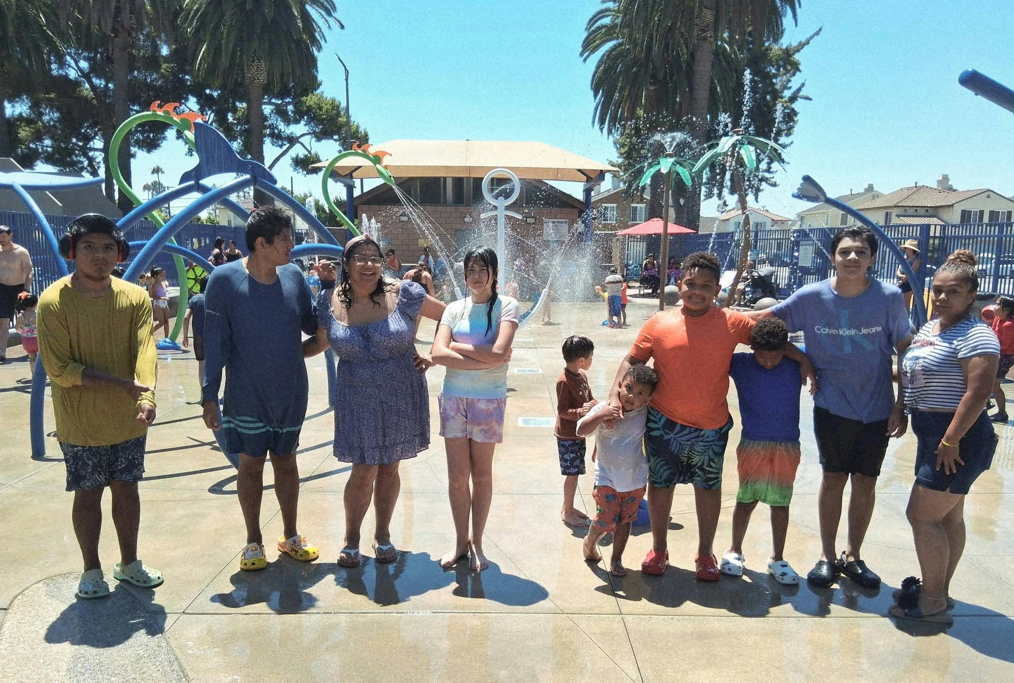 A group of people standing together at an outdoor splash pad on-campus splash pad