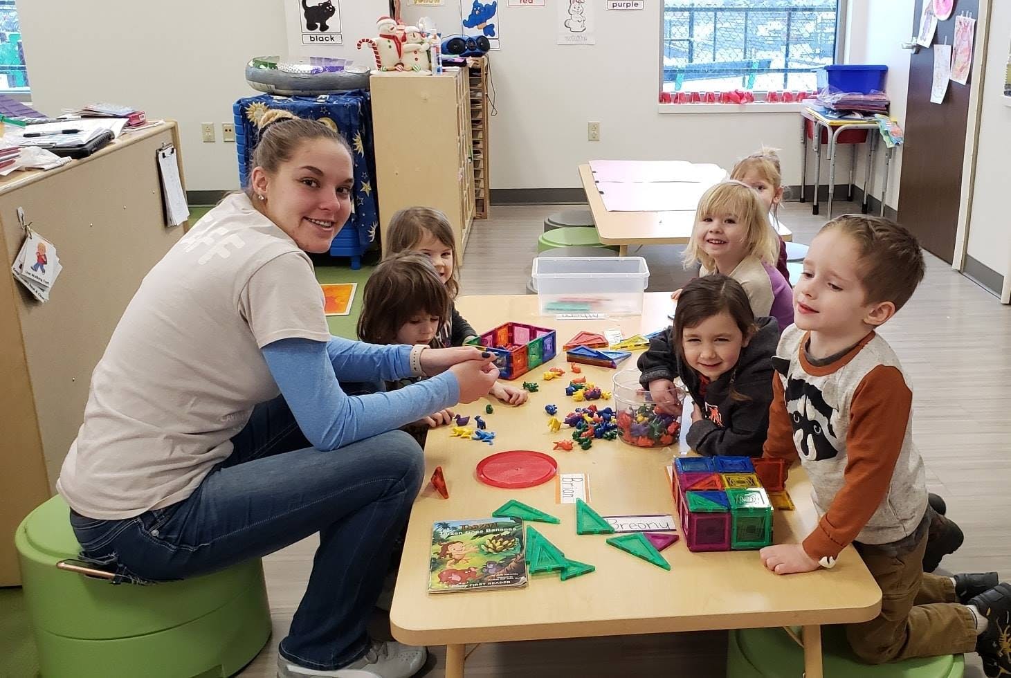 Adult and children playing with colorful blocks at a table in a classroom