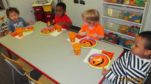 Four children sitting at a table with plates and cups